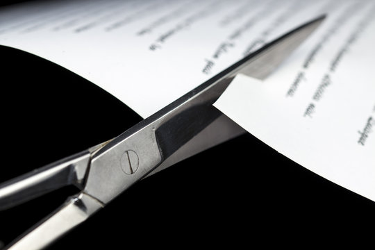Cutting a document with scissors, on black