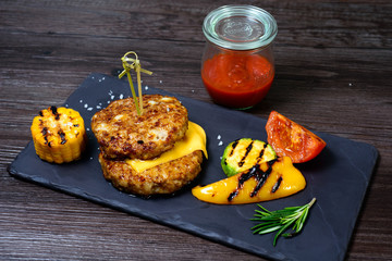 two fried cutlets next to peppers and tomatoes