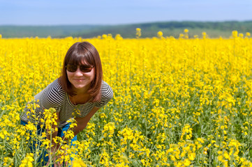 Fototapeta premium smiling girl among a field of yellow flowers