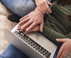 Young couple using a laptop lying on their bed