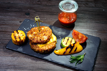 two fried cutlets next to peppers and tomatoes