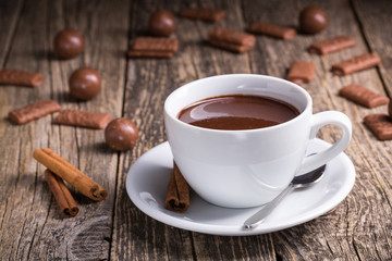 White cup of delicious hot chocolate with candies on table.