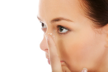 Beautiful young woman putting a contact lens