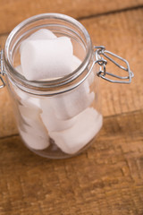 Sweet marshmallows in a glass jar on wooden table.