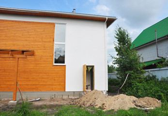 Fototapeta na wymiar House Construction with New Modern Passive House Facade Wall and Installing water supply system pipe in dirt trench.
