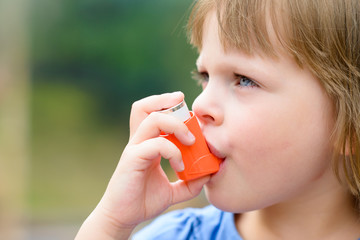 Portrait of a girl using asthma inhaler outdoors - obrazy, fototapety, plakaty