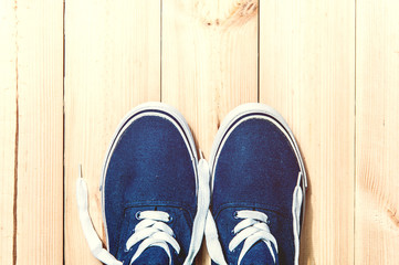 Blue sneakers on wooden background with copy space. Top view. 