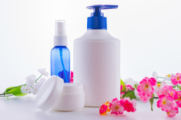 Obraz na płótnie Canvas cosmetical tools. jars of cream for hands to the face with flowers on a white background