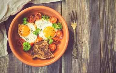 Fried eggs with cherry tomatoes and parsley in clay dish