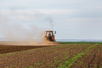 Fototapeta premium Tractor cultivating field at spring