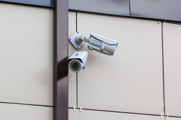 two security cameras on beige wall