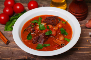 National Greek dish stifado with beef, tomatoes and onions, stewed in red wine with Herbs on a wooden background, horizontal