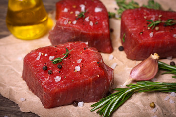 Raw beef steak with rosemary, thyme and garlic on wooden background
