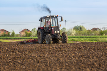Fototapeta premium Tractor cultivating field at spring