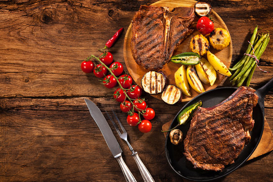 Beef steaks with grilled vegetables on wood