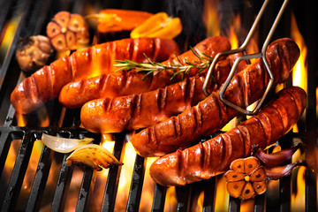 Saucisses sur la grille du barbecue avec des flammes