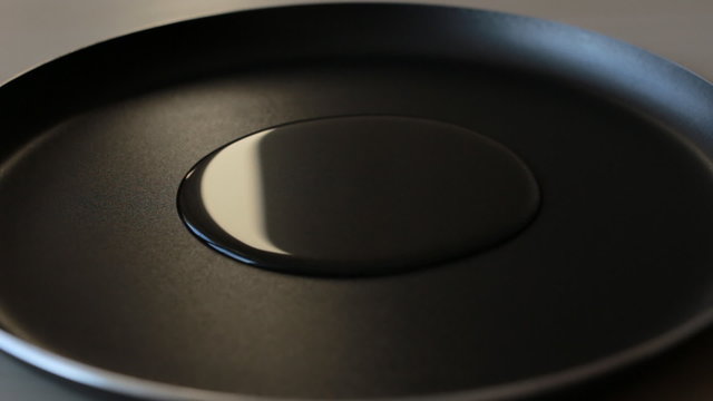 Pouring oil into a black frying pan