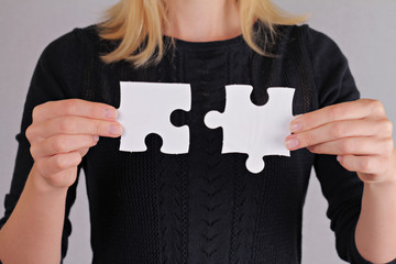 Solutions, partnership concept. Woman holding two pieces of a blank puzzle