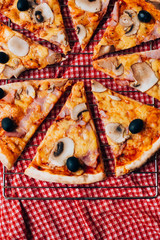 Parts of pizza salami and mushroom served on a tablecloth on an wooden kitchen table surrounded by the brush and paints, overhead view with copyspace. Food like arts