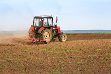 Fototapeta premium Tractor cultivating field at spring