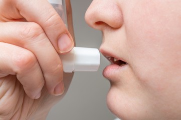 Asthmatic woman is using inhaler.