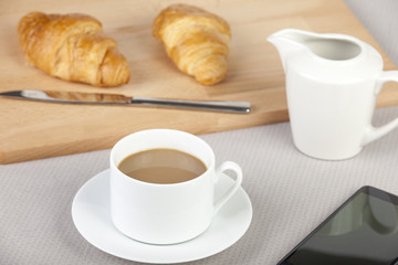 Cup of white coffee with fresh golden croissants