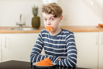 Boy at Table with Mouthful of Shredded Carrots © Jan H. Andersen