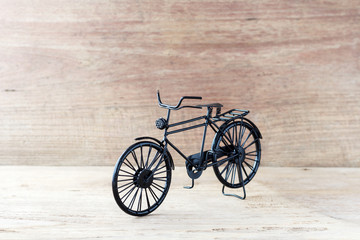 Fototapeta premium Vintage model black bicycle on old wooden table.