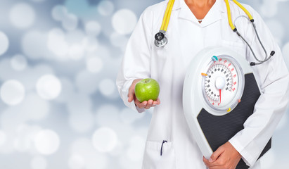 Doctor woman hands with scales and apple.