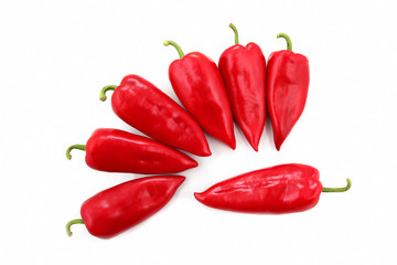 seven bright red sweet peppers on a white background