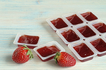  Strawberry marmalade.   Strawberry marmalade in plastic containers on a blue wooden background
 