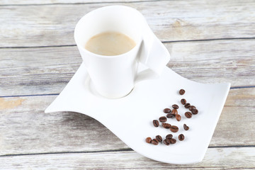 Elegant coffee cup with beans on wooden table