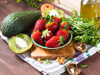 Ingredients for avocado salad with strawberries, kiwi, walnuts and arugula
