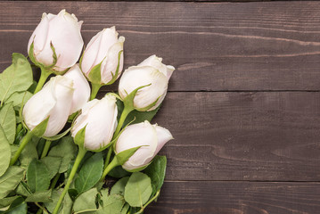 Beautiful light pink roses are on the wooden background
