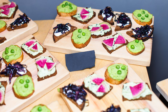 Wooden tray of appetizers on pallet coffee table at banquet with paper card for your text.