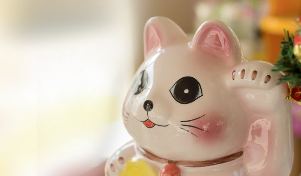 Maneki Neko cat. Common Japanese sculpture bring good luck to the owner over light [Blur and Select focus background]