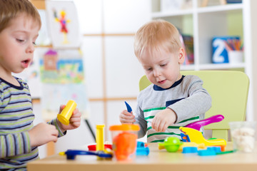 Happy children playing with plasticine at home or day care center