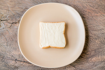 milk flavored cream spread bread slices in dish on wooden table
