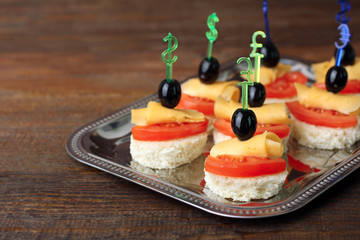 delicious canapes on iron spacing on brown wooden background