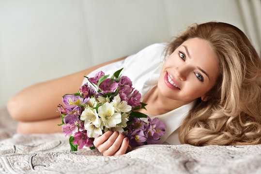 Beautiful young woman with flower bouquet. Spring portrait. At home. Interior. Mother's Day. Springtime