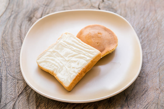 milk flavored cream spread bread slices and Dorayaki in dish on wooden texture