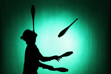 silhouette of a juggler with sticks on a blue background - obrazy, fototapety, plakaty