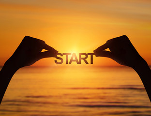Hands holding a start text in sea sunset.