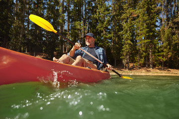 Mature man paddling a kayak in a lake