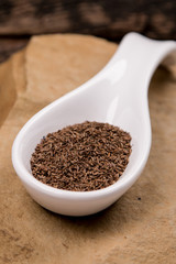 seeds or caraway in white spoon on stone