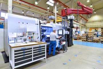 Arbeiter an einer modernen CNC Drehmaschine in einer Fabrik - bearbeitet Bauteile für die Industrie // Worker at a modern CNC lathe in a factory