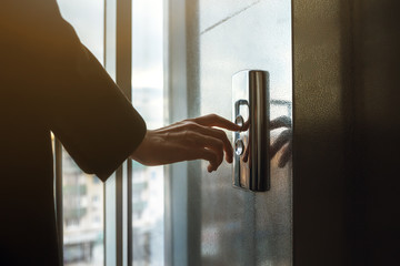 finger presses the elevator button. Red button. sunset light. businessman is a lift. high floor....