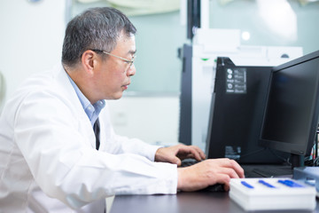 Asian old man analysises experimental data in lab