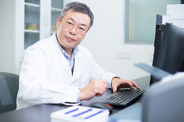 Asian old man analysises experimental data in lab