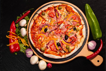 Pizza served on wooden board and raw ingredients